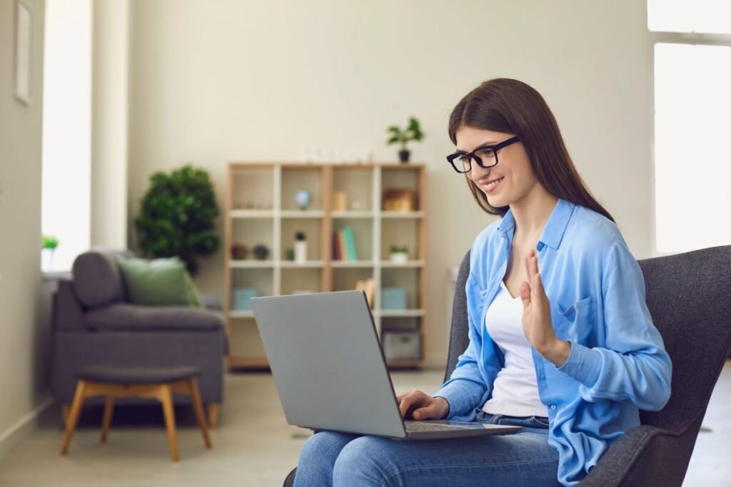 Femme souriante en visioconférence sur son ordinateur portable, illustrant un coaching en ligne pour retrouver confiance après une rupture professionnelle.