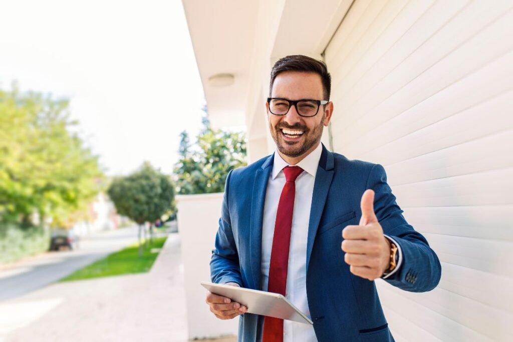 Cadre confiant en costume bleu donnant un signe de réussite et tenant une tablette