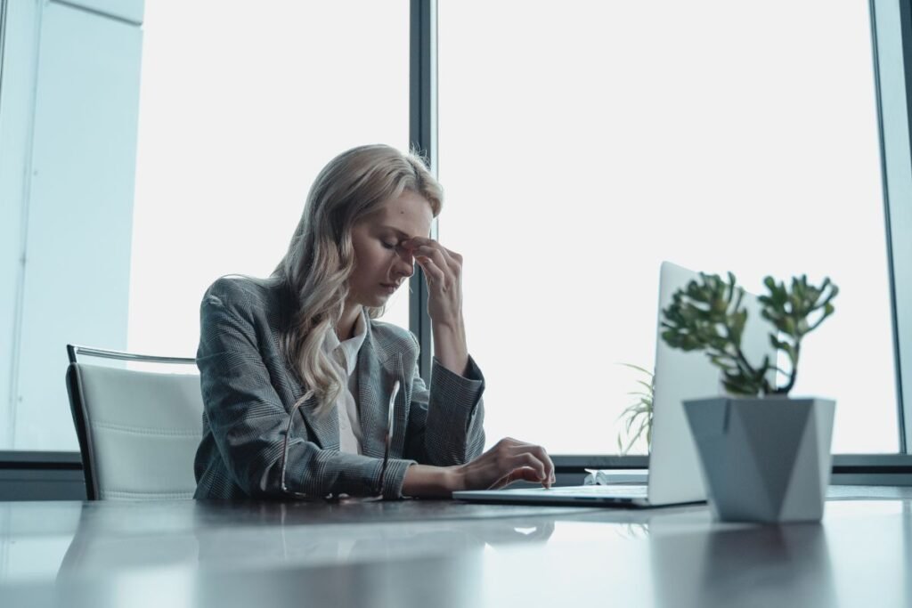 Dirigeante d’entreprise fatiguée, en surcharge mentale au bureau, la tête dans les mains