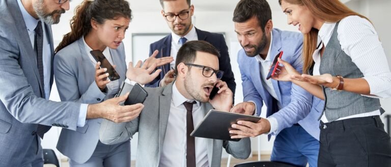 Cadre en costume gris débordé par des sollicitations multiples de ses collègues dans un bureau