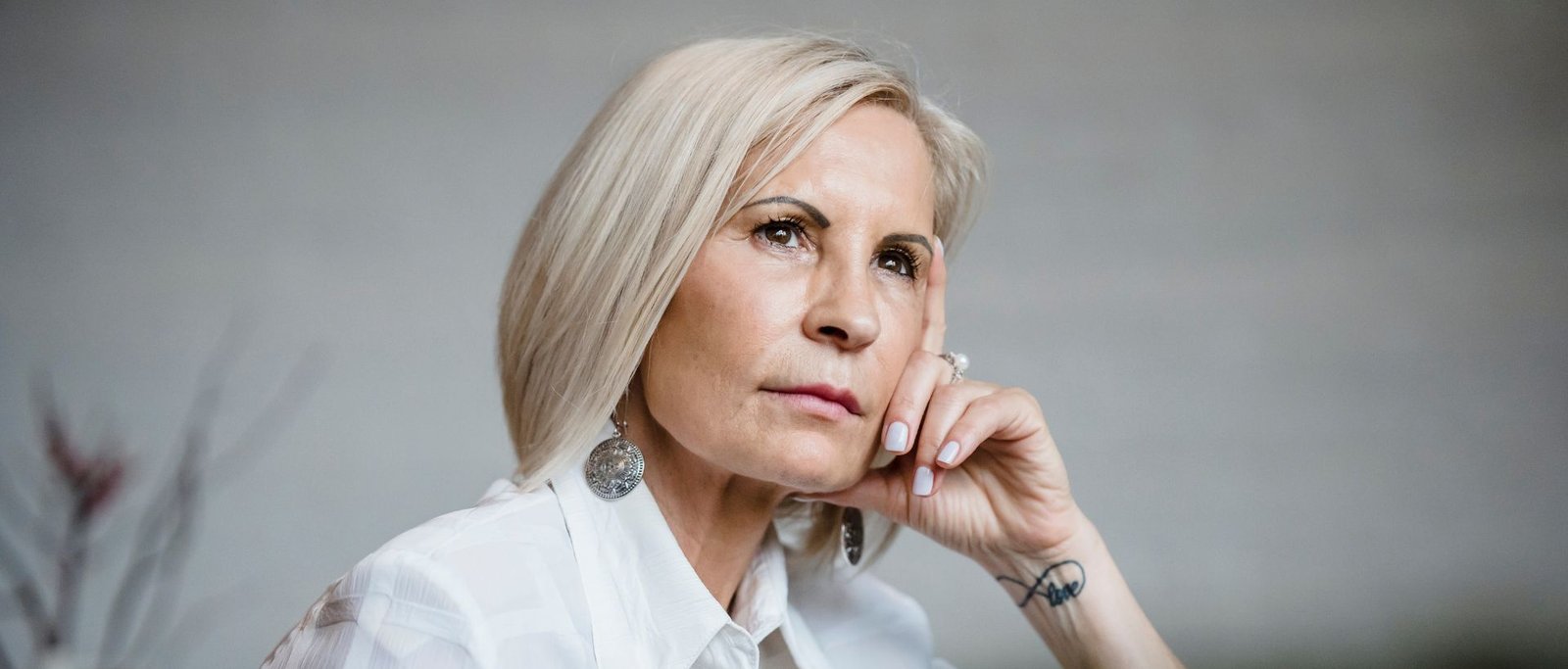 Portrait d’une femme de 52 ans, cadre marketing dans une grande foncière, en réflexion sur sa carrière, le regard tourné vers la lumière.