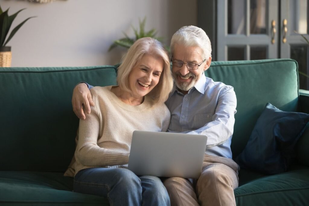 Couple de seniors souriant devant un ordinateur après une séance de coaching sur la retraite