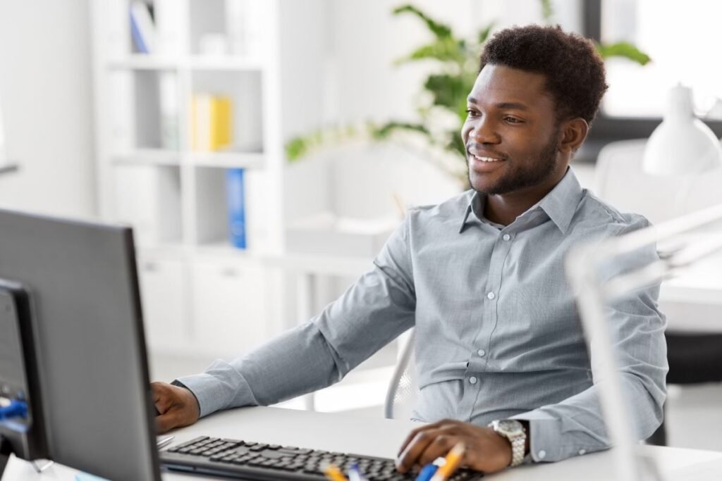 Homme souriant devant son ordinateur pendant une séance de coaching stratégique, symbole d’équilibre vie professionnelle et personnelle.
