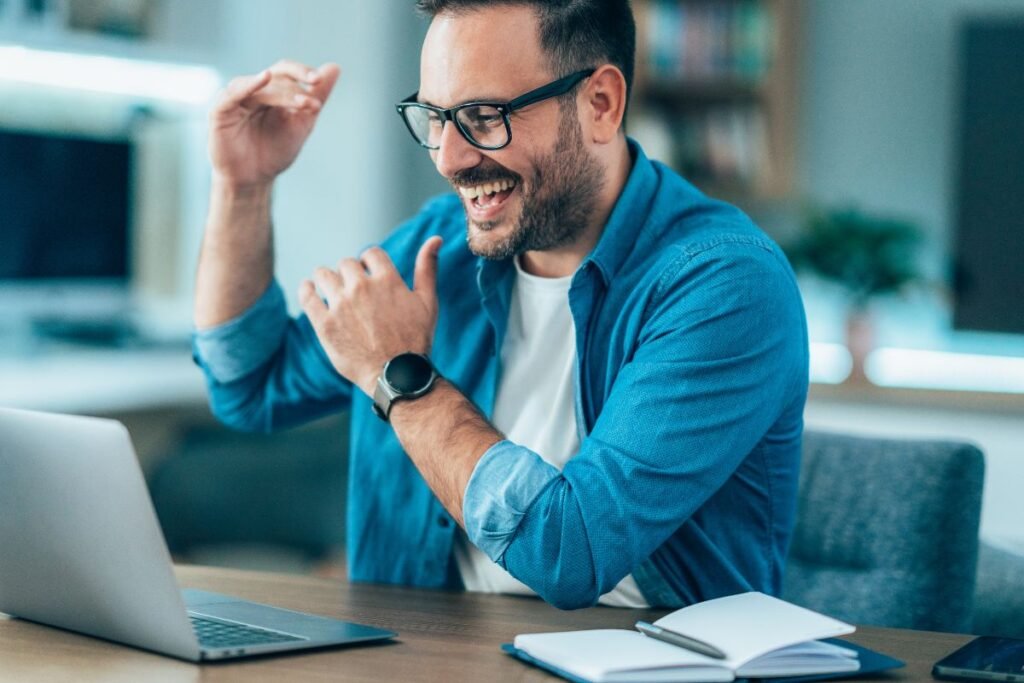 Homme souriant devant son ordinateur pendant une séance de coaching en visioconférence.