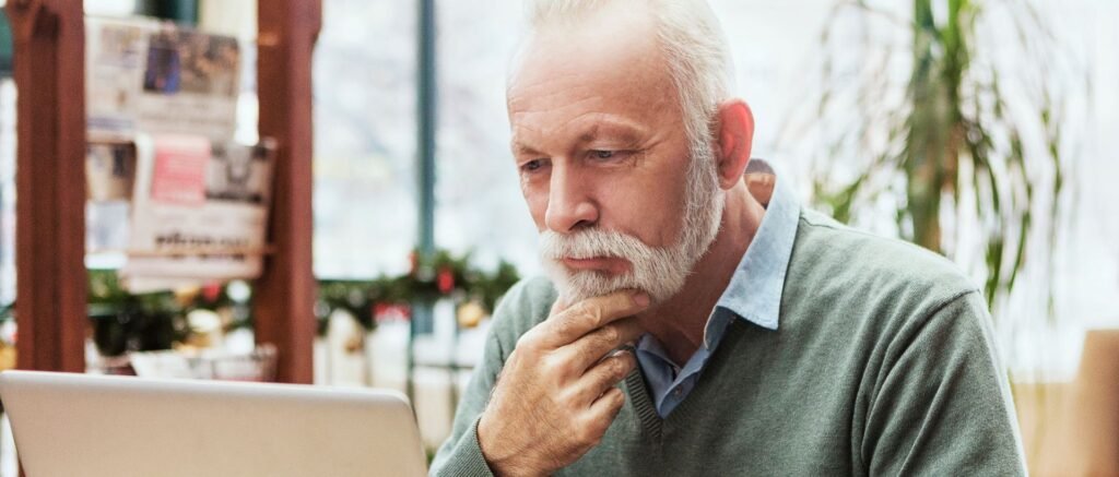 Homme senior pensif devant son ordinateur, illustrant la perte de repères au moment du départ à la retraite