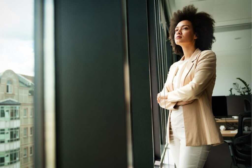 Cadre en réflexion devant une fenêtre, illustrant les causes de la stagnation professionnelle.