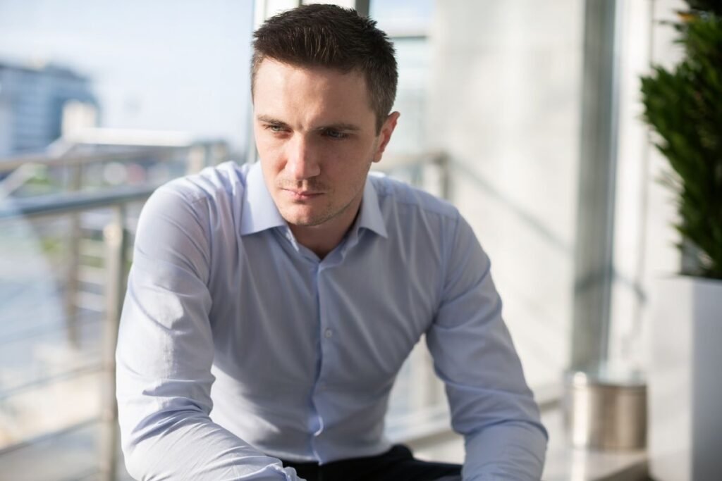 Cadre en chemise assis, l’air préoccupé par sa stagnation professionnelle.