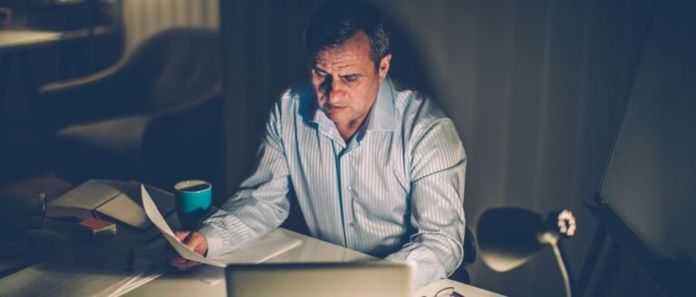 Dirigeant seul devant son ordinateur la nuit, submergé par trop de décisions à prendre.