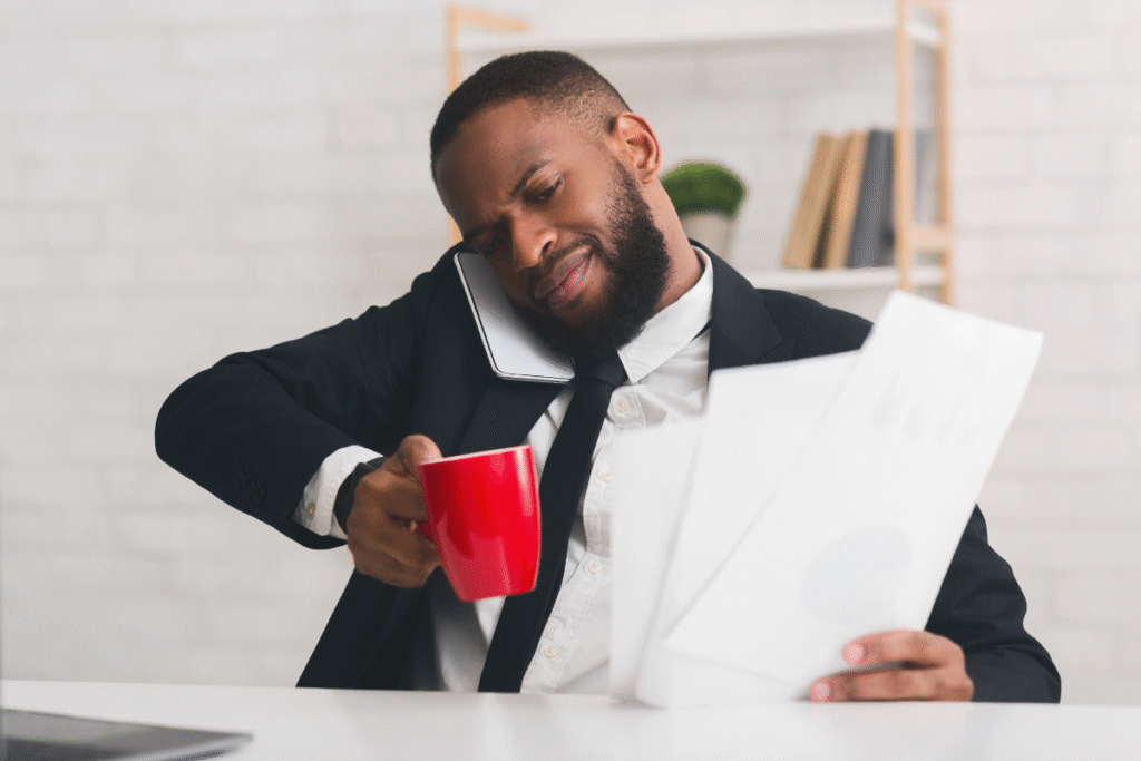 Cadre débordé jonglant entre appels, dossiers et café, sans temps pour réfléchir.