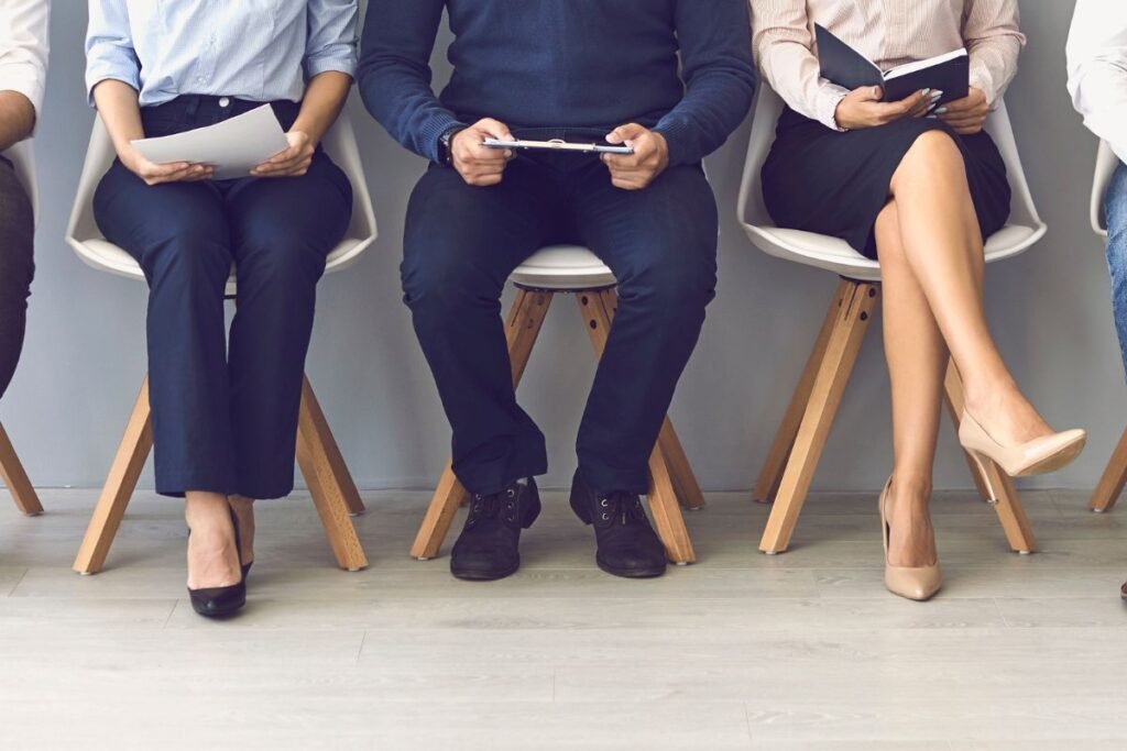 Collaborateurs assis en salle d’attente illustrant les conséquences des restructurations et licenciements sur les salariés.