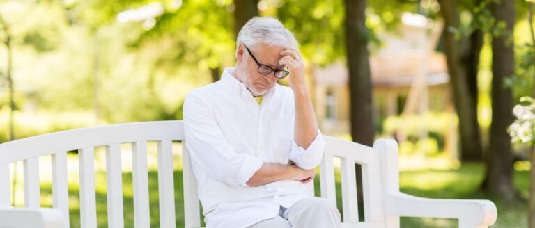 Homme senior assis sur un banc, pensif, illustrant le sentiment d’inutilité après la retraite.