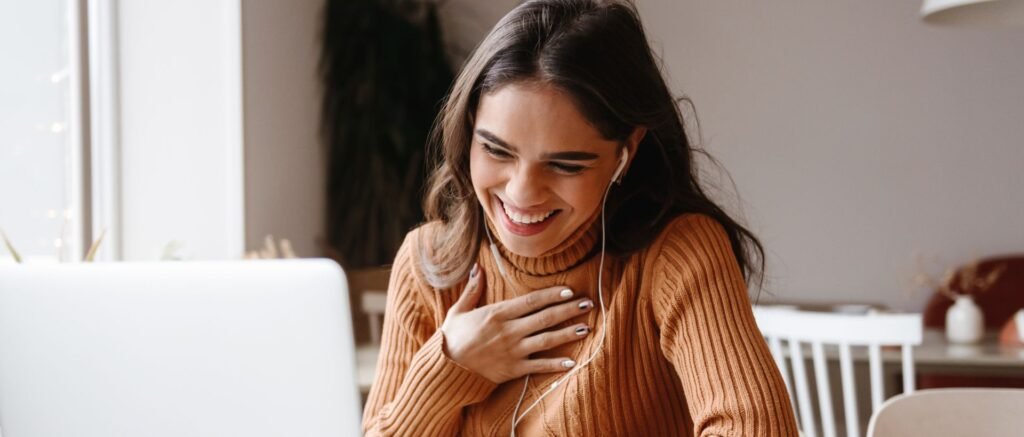 Femme en visioconférence souriante pendant un coaching sur l’équilibre vie professionnelle et personnelle.