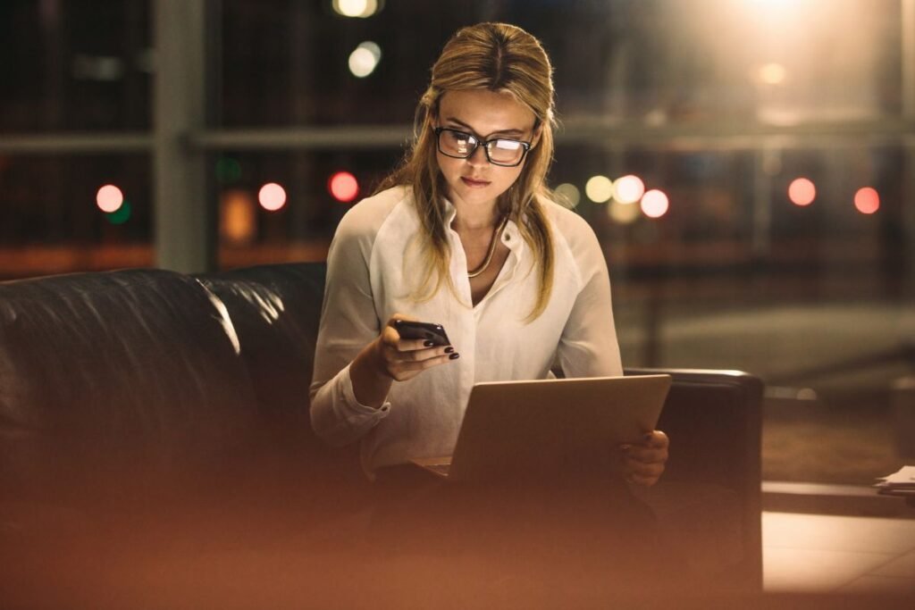 Cadre dirigeante travaillant tard le soir, submergée par les notifications et la charge mentale professionnelle.