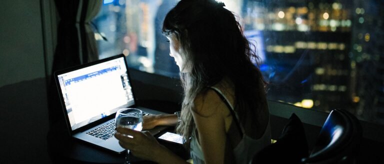 Femme travaillant tard le soir devant son ordinateur, symbole du travail qui déborde et fragilise la vie de couple.